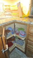 Plastic storage containers with various colored lids inside corner cabinet shelves and stacked on counter