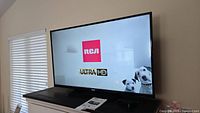 RCA Ultra HD 50-inch TV turned on displaying RCA logo and Ultra HD text with image of two dogs.