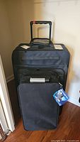 Front view of large Samsonite suitcase with extended handle and smaller black trunk organizer in front.