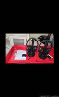 Two black Sony wireless stereo headphones on their individual charging stands, along with power adapter and operating instructions on a red tray.