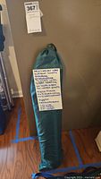 Green folded tomato greenhouse cover stored in a drawstring bag with handwritten note describing the item and its dimensions.