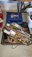 Full view of toolbox containing assorted hand tools such as screwdrivers, wrenches, hammers, and files, also includes screws and small parts