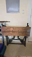 Shows full front view of the wooden workbench with metal base and built-in wooden vise on the left.