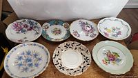 Top view of 7 small antique porcelain dishes with different floral patterns and colors.