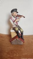 Front view of the Lefton porcelain fiddler figurine sitting on brick chimney base, playing violin, showing the detailed paint and colors.