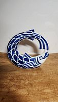 Side view of the vintage Sargadelos circular fish porcelain figurine showing detailed blue and white scale pattern, positioned on wooden surface against white background.