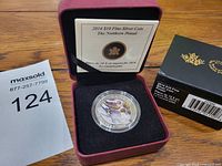 2014 The Northern Pintail $10 fine silver coin displayed in maroon presentation case with certificate and original box on a wooden surface next to a MaxSold bid tag number 124.