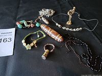 Photo shows a variety of Asian collectible items including beaded bracelets, carved stone beads, and a small statuette on a black fabric background.