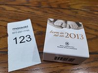 Original white outer box with baby feet image and 'born in 2013' text, showing packaging condition.