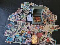 Loose vintage sports trading cards scattered around a green metal storage box