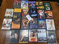 Photo showing full lot of 22 DVDs and Blu-Rays arranged on wooden table surface, various movie and concert titles visible.