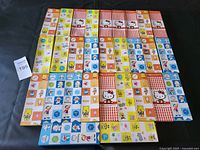 Full view of all six boxed kid's cutlery sets arranged on a surface displaying colorful themed boxes featuring characters such as Hello Kitty, Winnie the Pooh, Doraemon, and SpongeBob SquarePants.