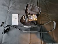 Panasonic Lumix camera with case and neck strap on black background from a distance