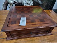 Top view of closed wooden game box with checkerboard pattern on lid.