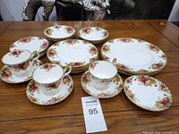 Stacked view of bowls, plates, cups and saucers on wood table.
