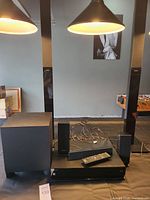 Full setup of the Sony home theater system showing the Blu-Ray player, subwoofer, speakers, remote, and wires on a black surface under warm lighting.