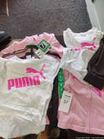 Photo of two Puma kids sports sets—t-shirts, leggings, and zip-up jackets in size 6 and 8 with tags included.