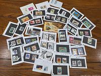 Photo showing a spread of multiple vintage Chinese stamps mounted on white cards with black backing, laid out on a wooden surface.