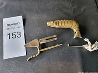 Photo of the vintage brass shrimp-shaped lock, showing the main body and locking mechanism separated.