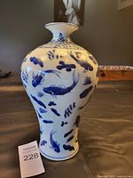 Front view of a blue and white ceramic vase with fish motif and aquatic decoration.