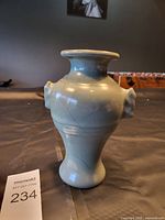 Front view of a light blue ceramic vase with two small handles and crackle glaze.