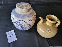 Photo of the two ceramic items on a black surface showing shape, color and decoration.