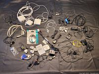 Wide view showing assortment of cables, adapters and earphones laid out on surface