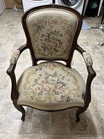 View from above showing tapestry upholstery on seat and back with floral designs, carved wooden frame with cabriole legs, and upholstered armrests.