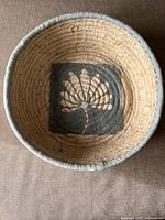Top view of basket interior showing floral design on dark square background and natural woven texture