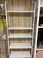 Full view of IKEA white metal shelving rack with five shelves, showing overall structure and shelf spacing.