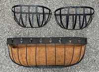Top-down view of three metal planter baskets, one large with coco liner, two smaller without liners, showing metal structure and condition