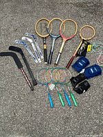 Overview of mixed sports equipment including rackets, sticks, protective gear, and jump ropes