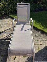 Front view of outdoor lounge chair showing metal frame and mesh seating with minor dirt spots.