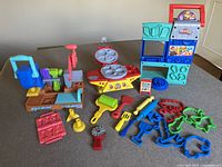 Full view of Play-Doh playsets including bakery, BBQ, and tool bench sets with multiple tools and cutters spread around.