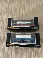Top and side view of two unopened model roller coaster boxes by STATIX with clear windows showing red/white and blue/gray coaster cars and track.