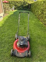 Front view of the red Toro lawn mower on grass with handle extended and engine visible