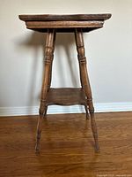 Side view showing turned legs and lower shelf, wooden floor background.