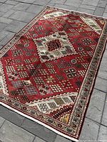 Overall top view of the red geometric rug laid on paving stones