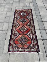 Full front view of runner rug laid flat on pavement showing geometric medallion pattern.