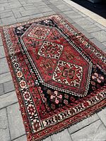 Full view of rug laid flat on stone patio showing overall pattern and colors.