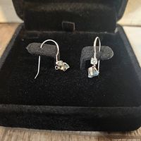 Pair of 14K white gold earrings with aquamarine and white sapphire stones displayed in black velvet jewelry box.