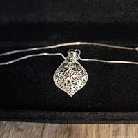 Close-up of 14K white gold pendant front showing floral filigree pattern