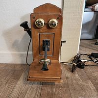 Front view of the novelty tube radio modeled as an old wooden telephone with brass bells and a black handset.