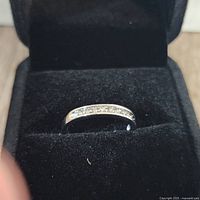 Front view of the sterling silver wedding band with channel-set diamonds inside black velvet box.