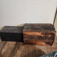 Photo showing a large wooden trinket box with worn finish and black metal box with latches.