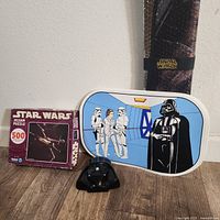 Photo showing the 500-piece Star Wars puzzle box, Darth Vader face blaster toy, and the metal Star Wars serving tray.