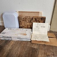 Two wooden cutting boards, one white plastic tray, two Slice Perfect system boxes, and Py Rak rack with instructions on wooden floor.