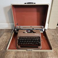 Opened Olympia SM3 typewriter inside its carrying case, showing the full machine and case interior.