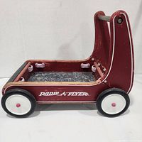 Side view of the red Radio Flyer toddler pushcart showing the logo and wheels.