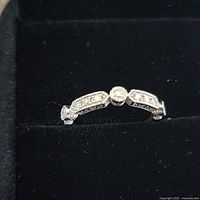 Close-up of the sterling silver ring showing nine small diamonds inlaid on the band with milgrain detailing, photographed on a black velvet surface.